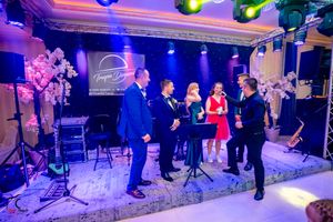 Wedding reception venue illuminated with vibrant purple and green lighting creating a dramatic atmosphere.