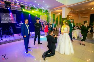 Wedding party dancing in an elegant ballroom illuminated by vibrant colored lights.