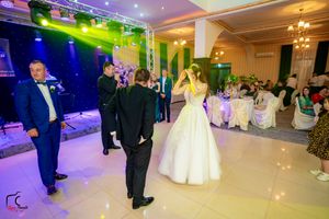 Wedding celebration in a grand ballroom with dynamic lighting and guests enjoying the festivities.