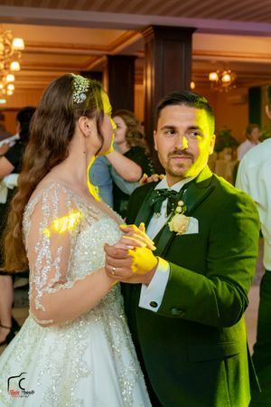 Couple sharing a dance moment under dramatic yellow and green lighting at their wedding reception.