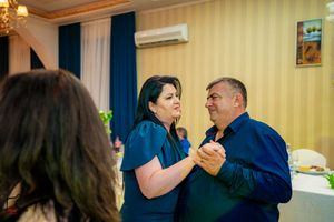 Couples dance together at an elegant reception venue with warm lighting and striped wallpaper.