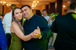 Couples slow dancing in a banquet hall with chandelier lighting and festive atmosphere.