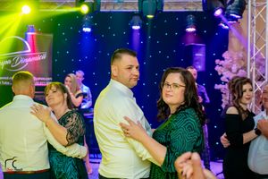 Colorful dance floor lighting illuminates couples dancing at an evening celebration.
