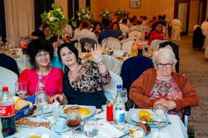 Wedding reception guests enjoying dinner at decorated tables in a banquet hall.