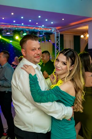 A couple dances together, with the woman wearing a green dress and man in white shirt.