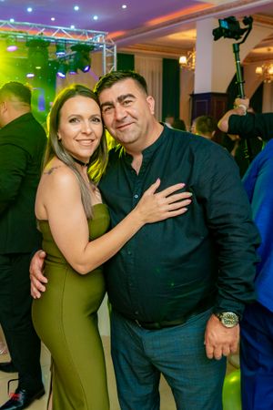 A couple poses together on the dance floor with green ambient lighting.