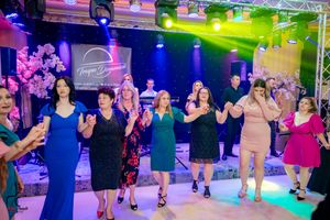 Dancers in formation moving to music under dramatic purple and green stage lighting.