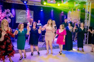 Line dancers practicing steps in unison during a social dance event with colorful lighting.