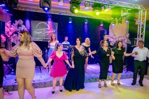 Social dancers performing synchronized moves in a line under mixed colored stage lights.