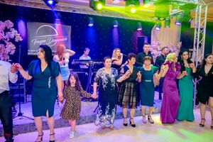 Dance floor filled with participants doing synchronized line dance steps under vibrant lights.