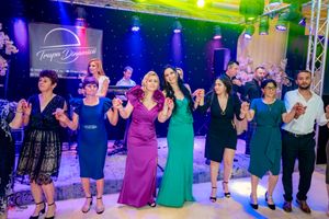 Large group performing synchronized dance moves at an elegant event with dramatic purple and blue lighting.