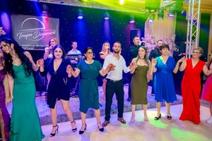 Event guests dancing in formation at a formal celebration with professional stage lighting and decor.