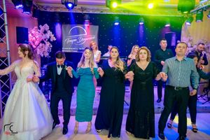 Formal event participants engaged in group dance routine under dramatic stage lighting.