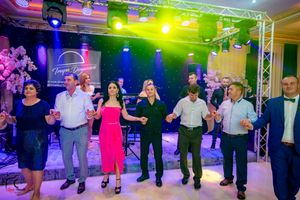 Guests participate in a group dance routine under colorful stage lighting at an indoor celebration.