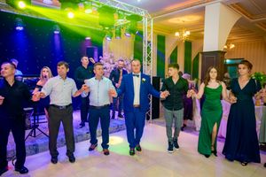 Elegantly dressed guests perform synchronized dance moves at an indoor venue with professional lighting.