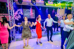 Energetic dance floor scene with party-goers dancing under professional stage lighting and truss systems.