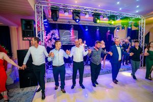 Large group dancing together at an indoor event space with professional lighting and sound equipment.