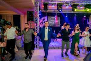 Social dance gathering with participants moving in formation under colorful stage lighting.