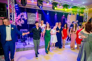 Festive dance celebration with participants in formal wear under theatrical lighting setup.