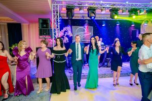 Social dance event with participants in formal attire dancing under dramatic purple and blue lighting.