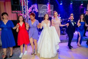 Wedding party dancing and celebrating in a ballroom with vibrant blue lighting effects.