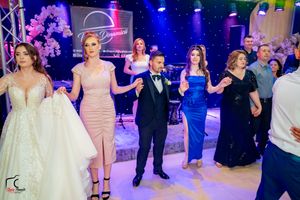 Panoramic view of a wedding reception with guests dancing under dramatic blue lighting.