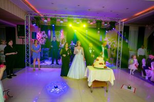 Wedding reception hall with dramatic lighting showing dance floor and cake display area.