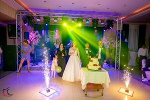 Wedding celebration with sparklers and cake display under multicolored venue lighting.