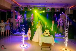 Wedding reception venue with colorful purple and green lighting effects illuminating an elegant ballroom setup.