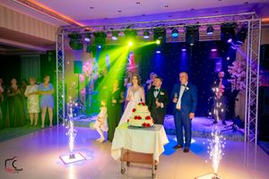 Elegant ballroom decorated with dramatic lighting effects and staging elements for a wedding celebration.