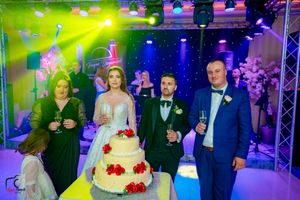 Wedding reception ballroom illuminated with vibrant lighting effects and decorated with elegant details.