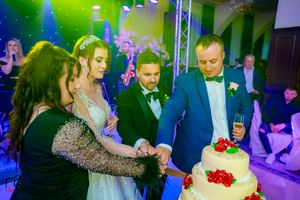Wedding party scene with dramatic lighting effects and a decorated white cake as the centerpiece.