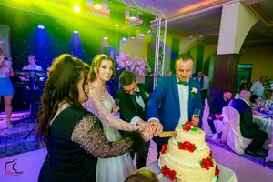 Reception hall decorated with dynamic lighting effects as wedding guests gather near the cake display.