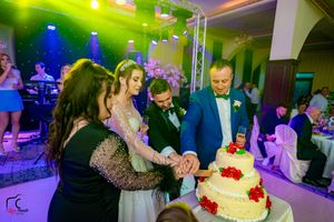 Wedding reception venue with professional lighting setup and guests celebrating near a tiered cake.