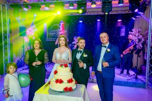 Wedding celebration with dramatic stage lighting and guests positioned around a decorated white cake.