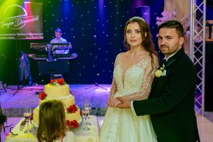 Elegant wedding reception scene with a decorated cake table under dramatic blue lighting effects.