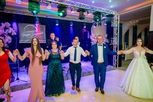 Wedding party performing synchronized dance moves under theatrical lighting at reception.