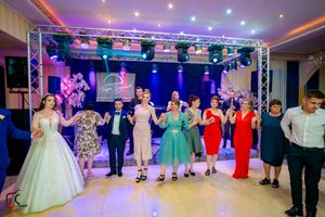 Wide shot of wedding reception dance floor with guests dancing under dramatic lighting effects.