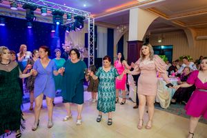 Wide view of a dance floor showing participants in a synchronized line dance under colorful lighting.