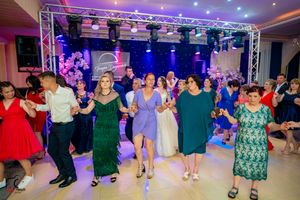 Wide angle view of a group dance performance in a ballroom with professional lighting setup.
