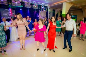 Wedding guests dance together on a colorfully lit dance floor during a reception celebration.