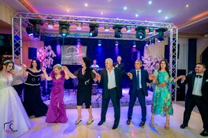 Dancers in formal attire perform synchronized moves on illuminated ballroom floor.