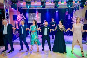 Reception attendees dance in formation under professional stage lighting at formal event.