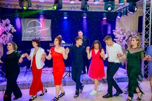Stage performance featuring dancers in red and green dresses under dramatic lighting.