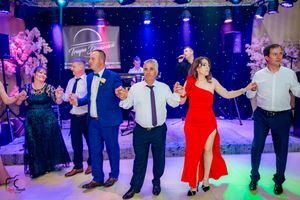 Party guests performing choreographed dance moves on a blue-lit dance floor at a formal celebration.