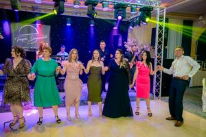 Party guests dancing in a line on a dance floor with colorful stage lighting.