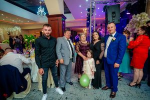 Wedding guests gather at a festive reception venue with colorful lighting and decorative columns.