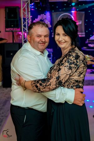 Couple dancing together at an evening reception with pink and blue lighting.