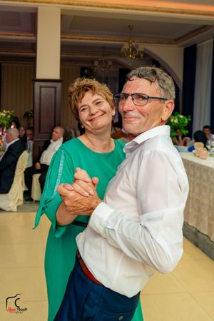 Dancing couple in green and white attire sharing a joyful moment.