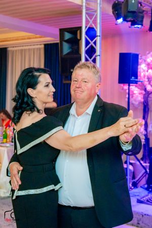 Couples dancing together at an elegant event with colorful lighting and stage equipment in the background.